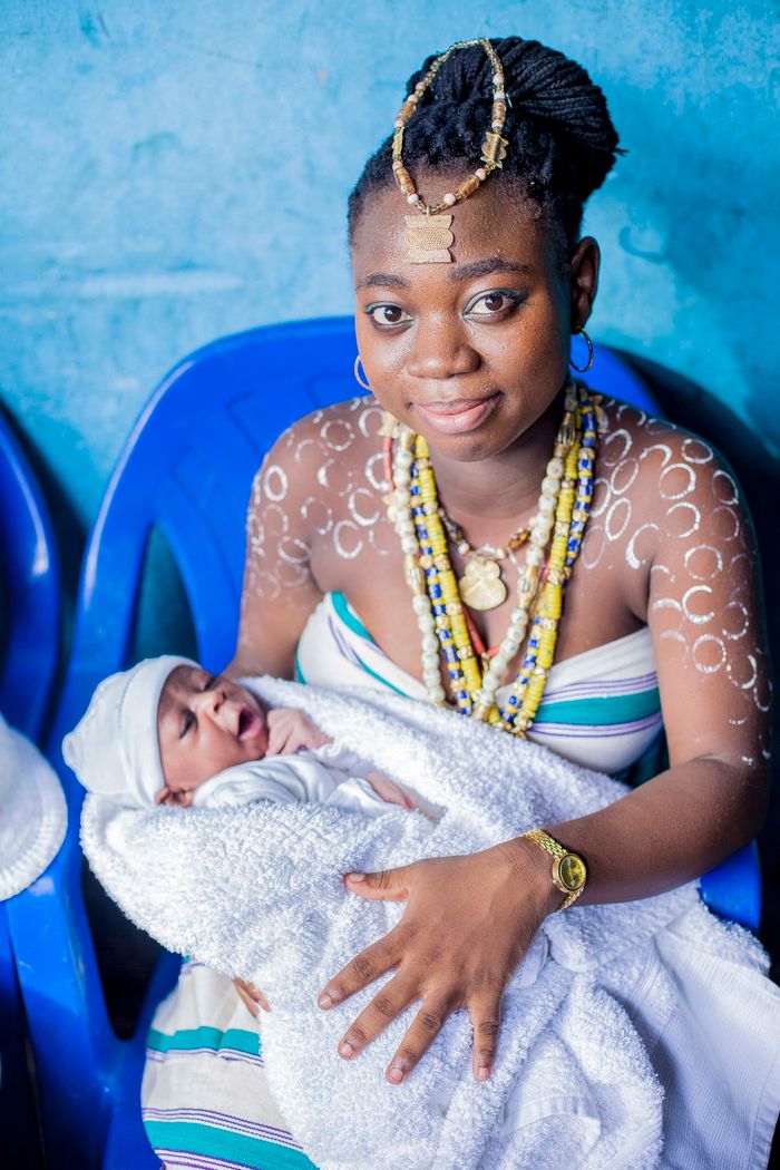 A woman in traditional attire holds her newborn, showcasing culture and motherhood.