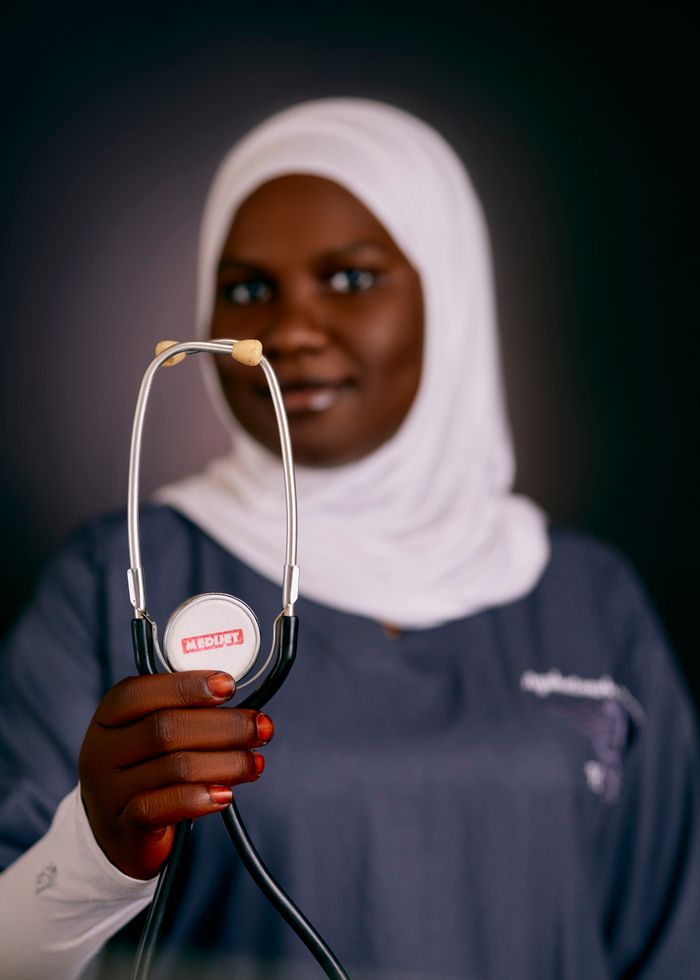 African female doctor in hijab holding a stethoscope, emphasizing health care.