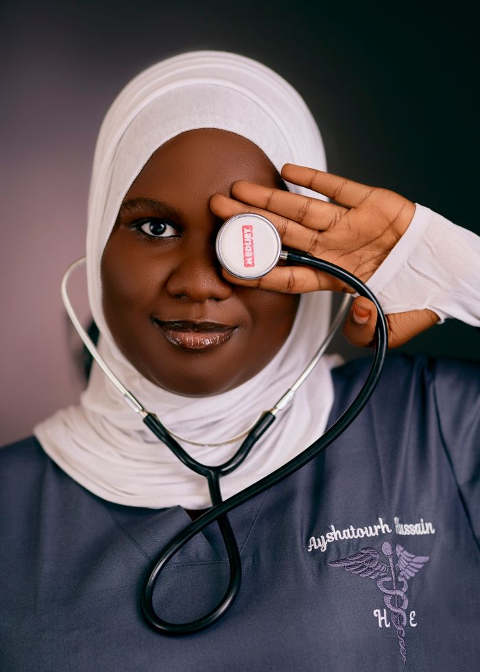 Confident female doctor wearing hijab and holding stethoscope over eye.