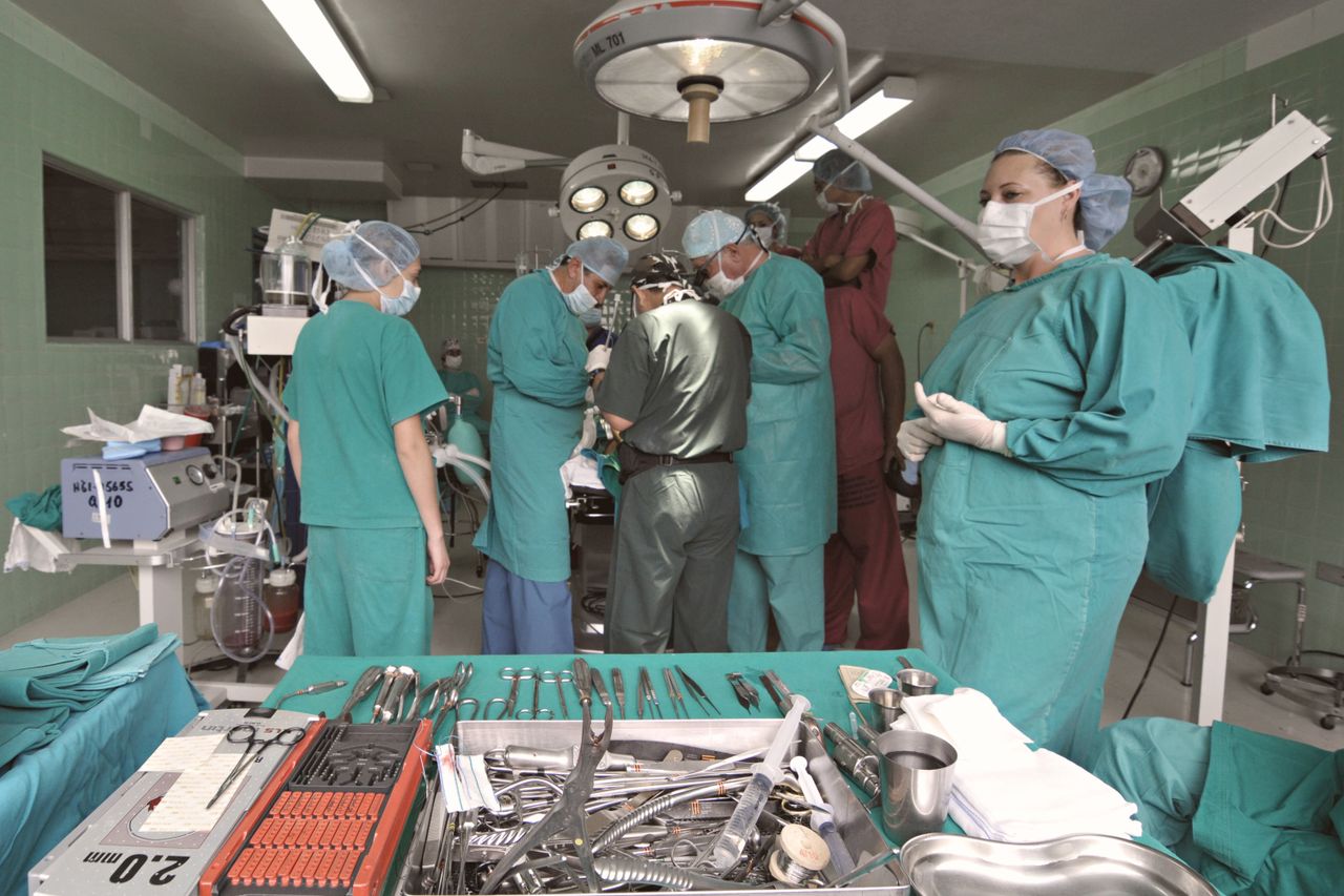 Medical team conducting surgery in a sterile operating room with surgical tools on display.